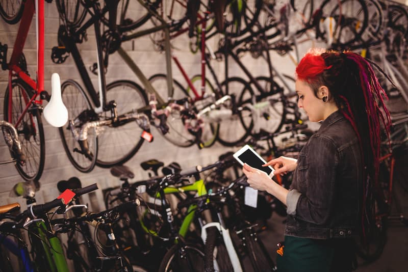 Frau wählt ihr Fahrrad mit Hilfe eines Tablets aus.