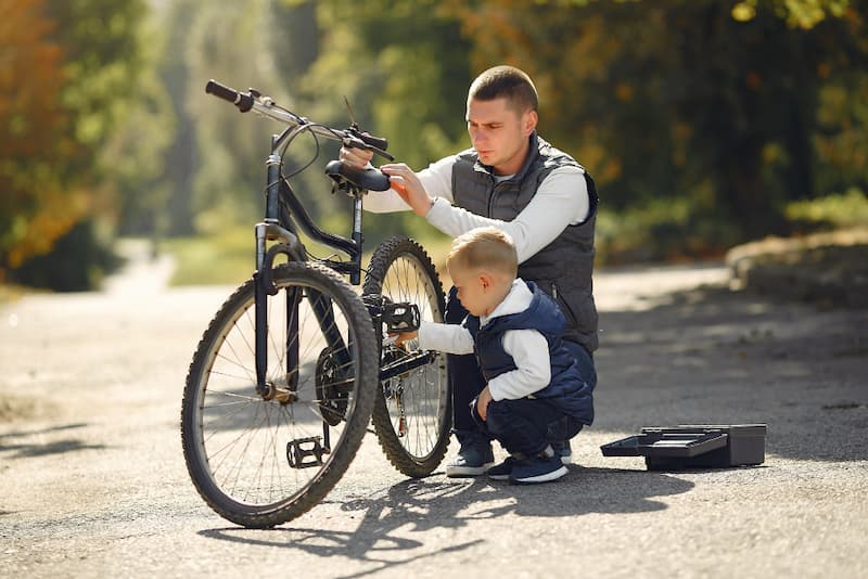 Vater und Sohn optimieren den Sitz eines Gravel Bikes auf der Straße.